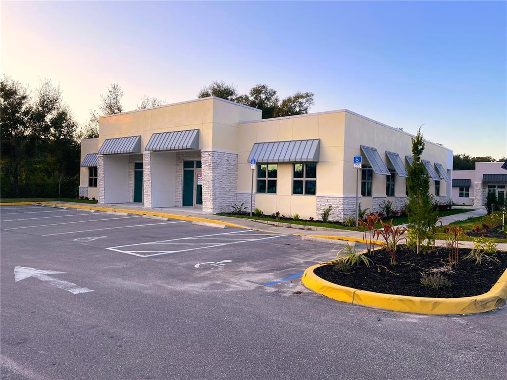 A single-story commercial building with light yellow walls, stone accents, and a paved parking lot — 871 HIGHWAY 466, LADY LAKE, FL
