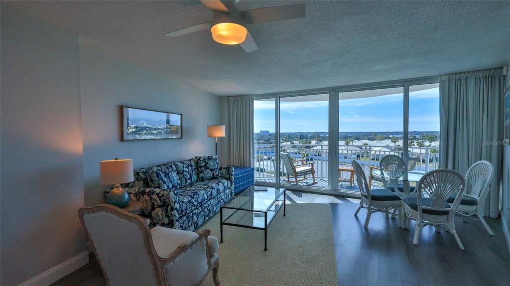 A living room features a floral sofa, glass coffee table, and balcony with water views — 2625 S ATLANTIC AVENUE UNIT 7SW, DAYTONA BEACH SHORES, FL