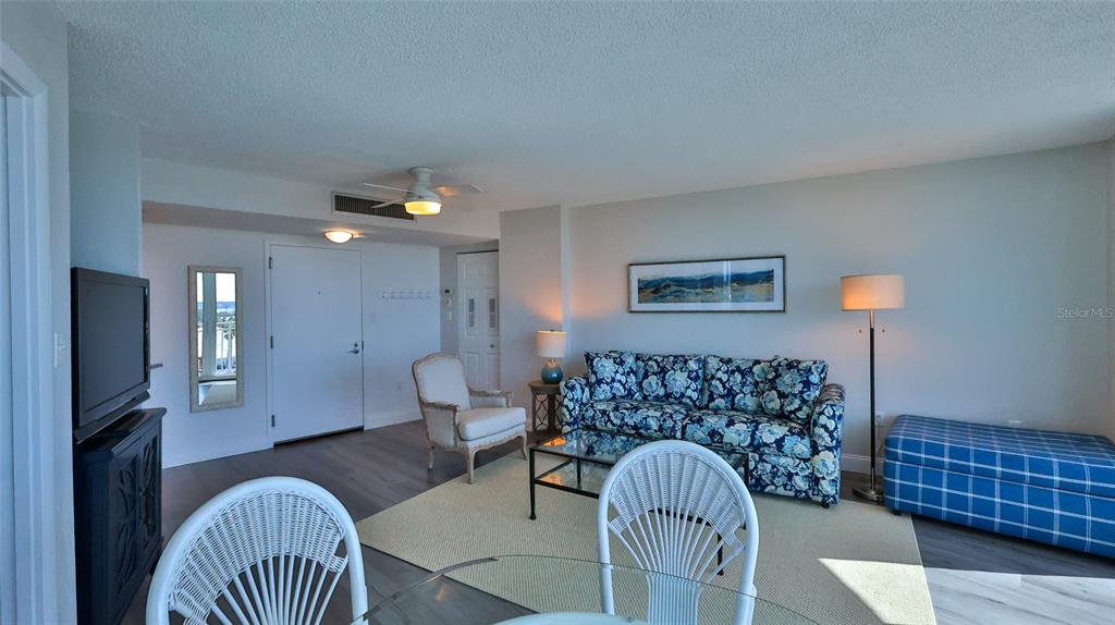 A living room features a floral sofa, a white armchair, and a blue plaid ottoman — 2625 S ATLANTIC AVENUE UNIT 7SW, DAYTONA BEACH SHORES, FL