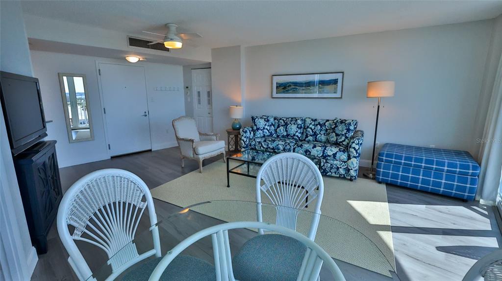 A living room features a floral sofa, a white armchair, and a glass dining table — 2625 S ATLANTIC AVENUE UNIT 7SW, DAYTONA BEACH SHORES, FL