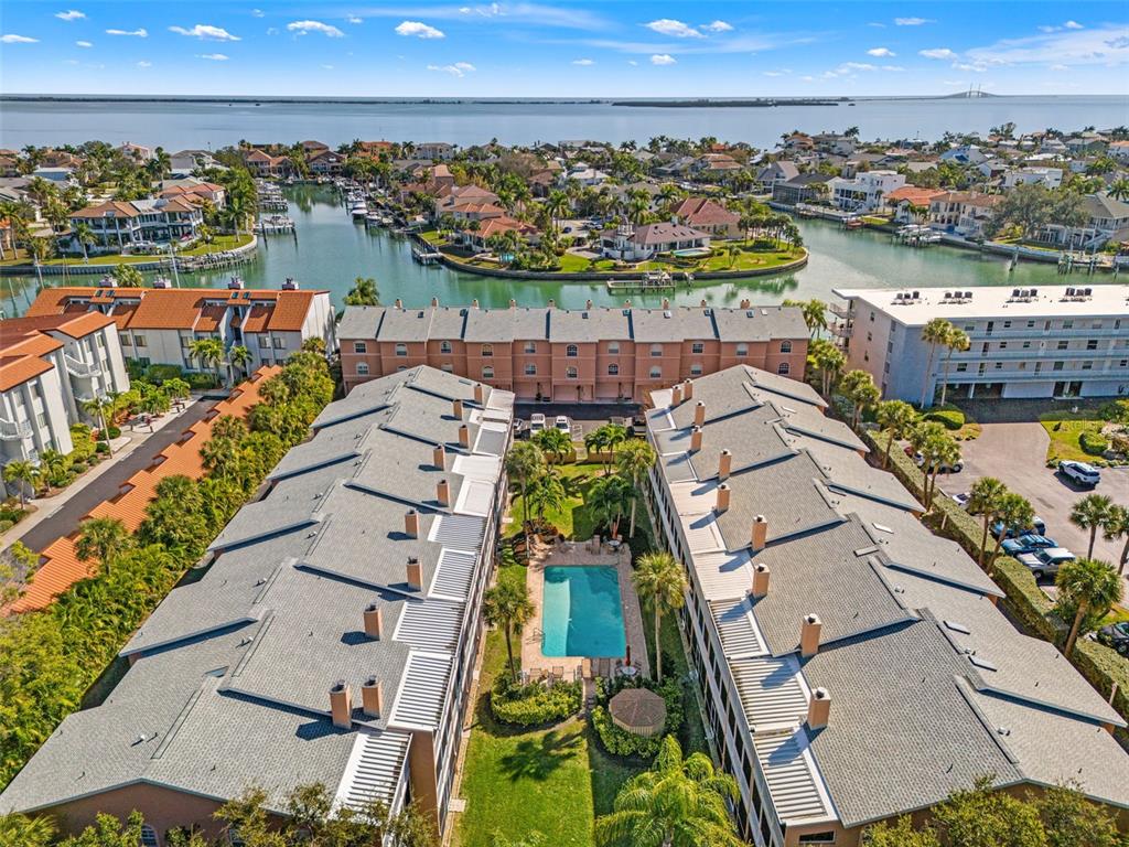 An aerial view shows two rows of townhomes flanking a central swimming pool and lawn — 637 PINELLAS BAYWAY S UNIT 111, ST PETERSBURG, FL