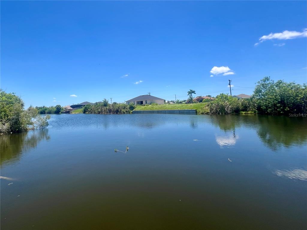 A view of a calm lake with houses and trees along the distant shoreline — 2208 NE 6TH AVENUE, CAPE CORAL, FL