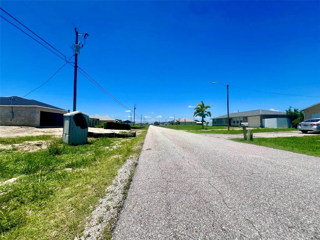 A paved residential street stretches into the distance under a clear blue sky — 2208 NE 6TH AVENUE, CAPE CORAL, FL