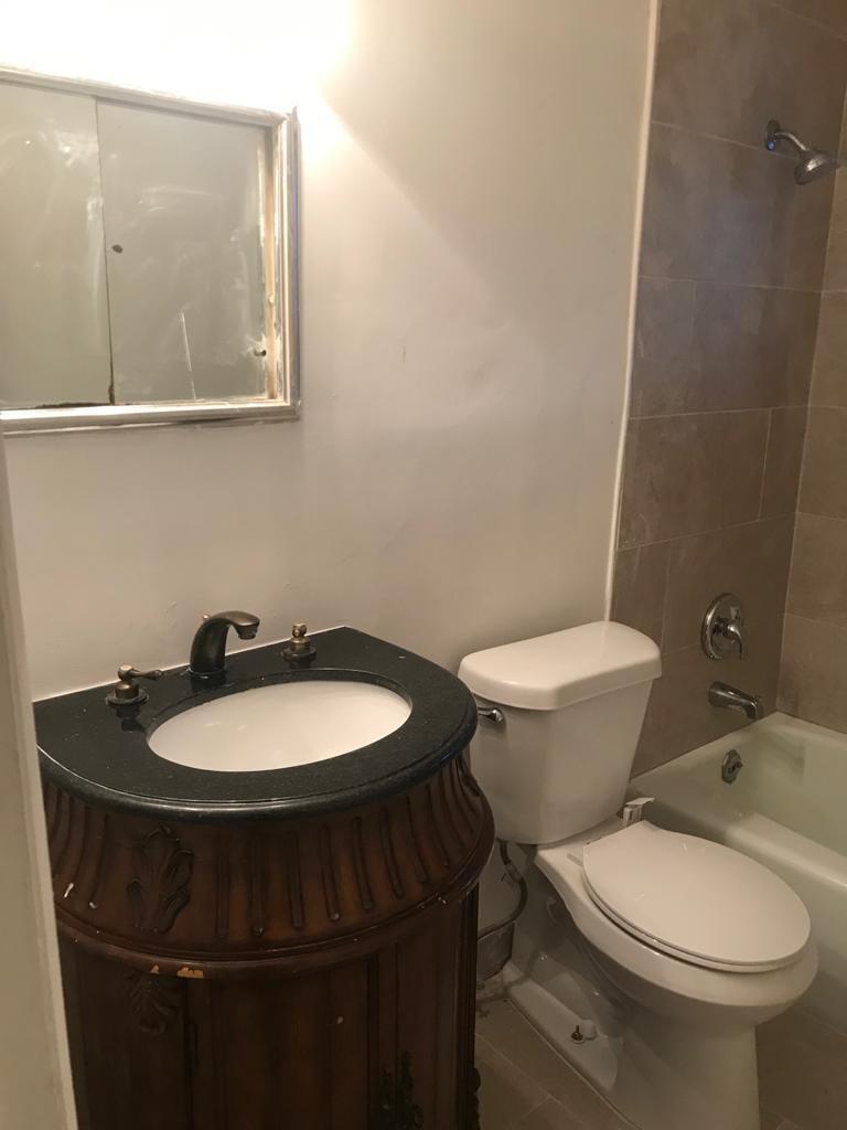 A bathroom featuring a dark wood vanity, black countertop, white toilet, and a tiled shower — DEERFIELD BEACH, FL