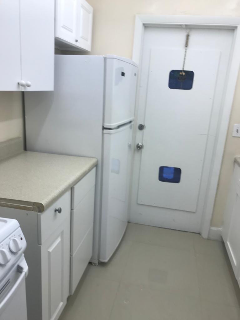 A kitchen features white cabinets, a white refrigerator, a countertop, and a white door — DEERFIELD BEACH, FL