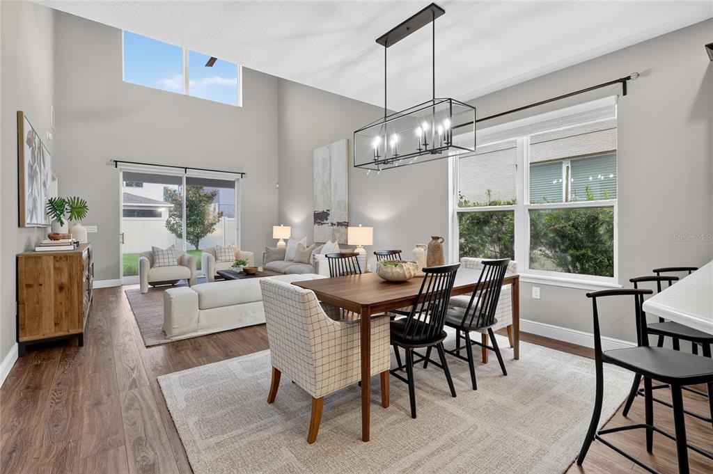 An open-concept dining and living area features high ceilings, wood flooring, and large windows — 517 RED ROSE LANE, SANFORD, FL