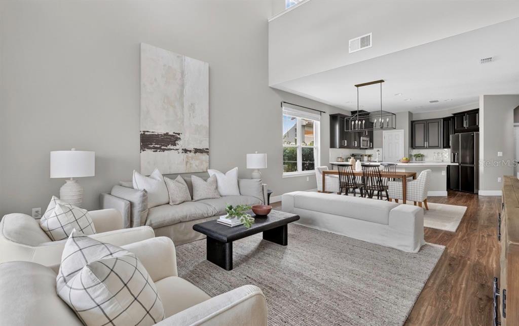 A living room with high ceilings flows into an open kitchen with dark cabinetry — 517 RED ROSE LANE, SANFORD, FL