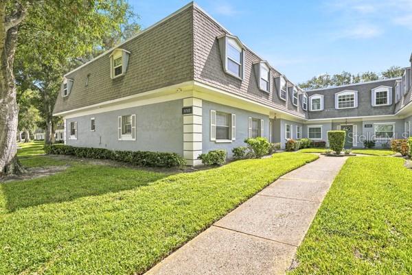 A two-story apartment building with a gray exterior and a shingled mansard roof — 1717 BELLEAIR FOREST DRIVE UNIT A, CLEARWATER, FL