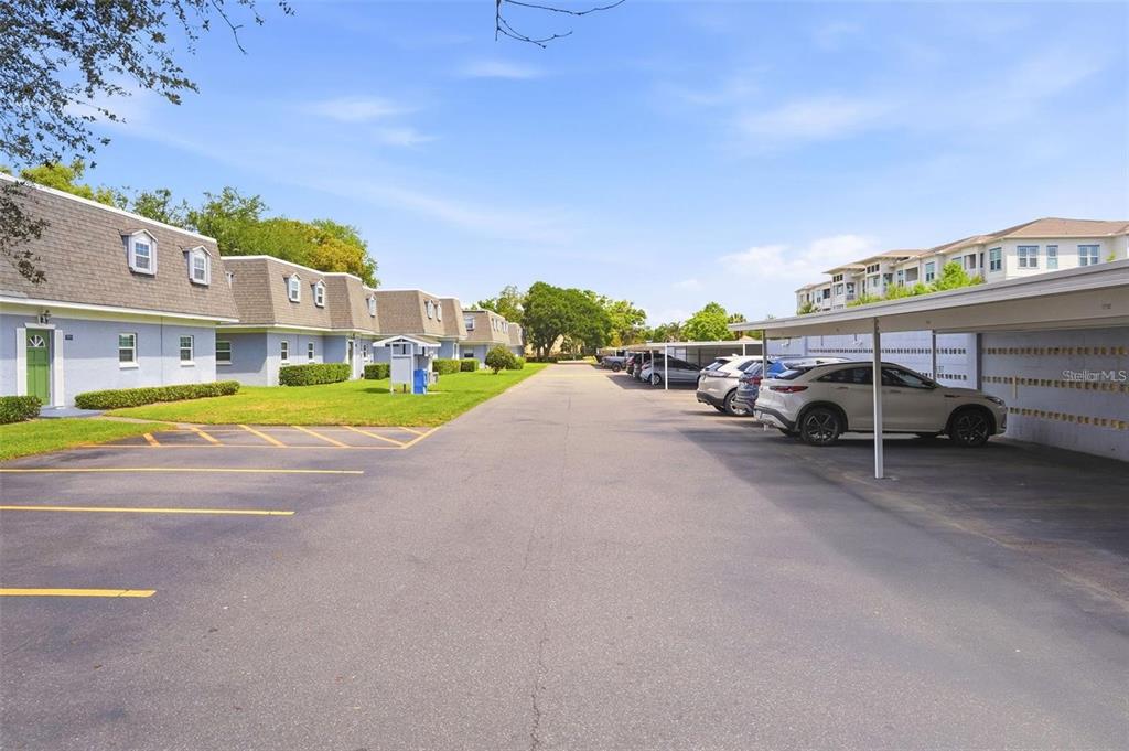An exterior view of a multi-unit apartment complex with covered parking and a paved driveway — 1717 BELLEAIR FOREST DRIVE UNIT A, CLEARWATER, FL