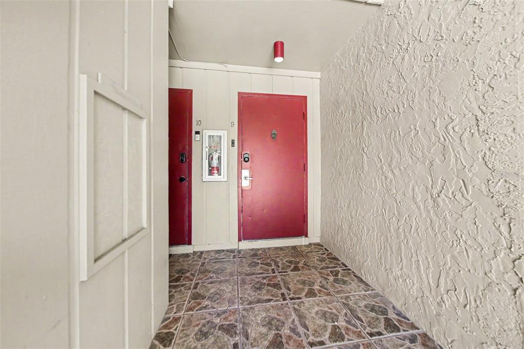 An exterior entryway features two red doors, a fire extinguisher cabinet, and tiled flooring — 429 SHEOAH BOULEVARD UNIT 9, WINTER SPRINGS, FL