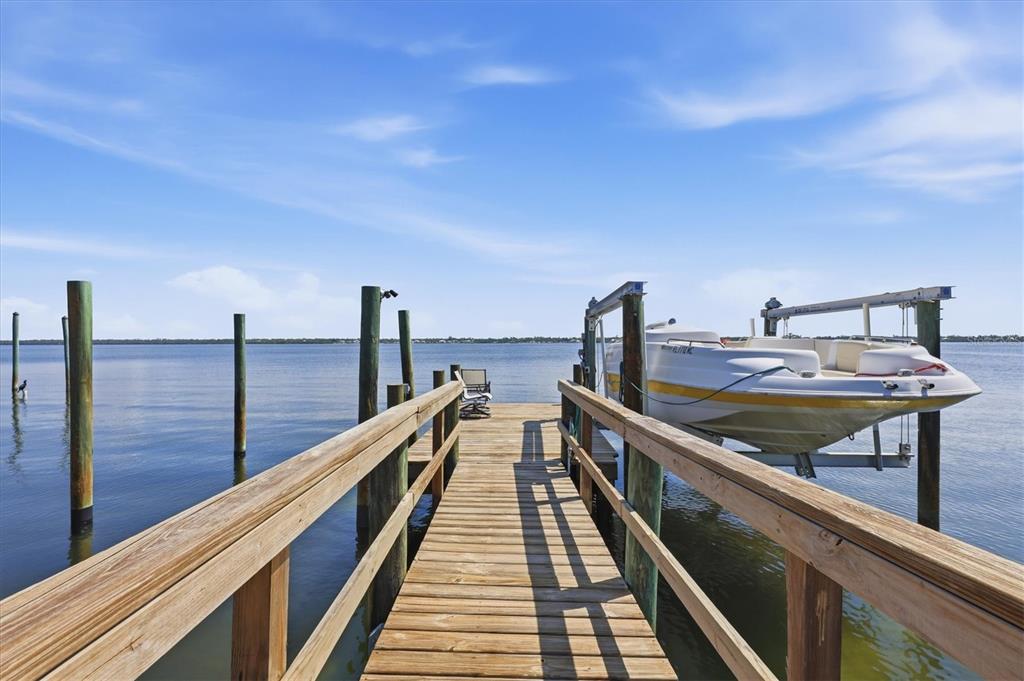 A wooden dock extends over the water toward a boat on a lift — 6421 MANASOTA KEY ROAD, ENGLEWOOD, FL