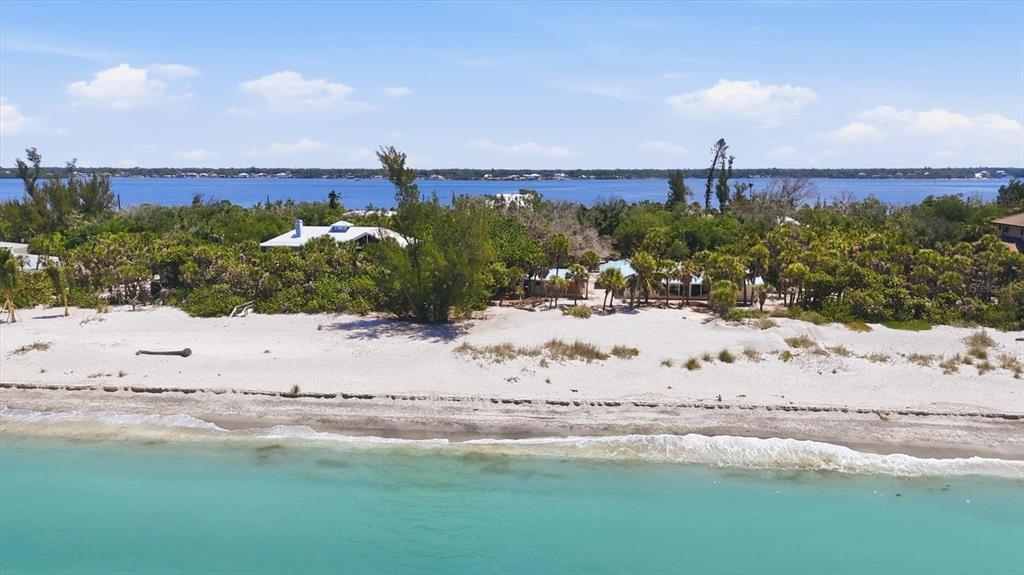 An aerial view of a beachfront property with houses nestled among trees along the coast — 6421 MANASOTA KEY ROAD, ENGLEWOOD, FL