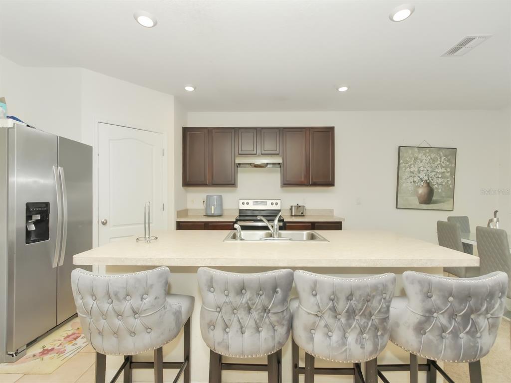 A kitchen features dark wood cabinets, a large island with a sink, and four barstools — 714 AUBURN GROVE COURT, AUBURNDALE, FL