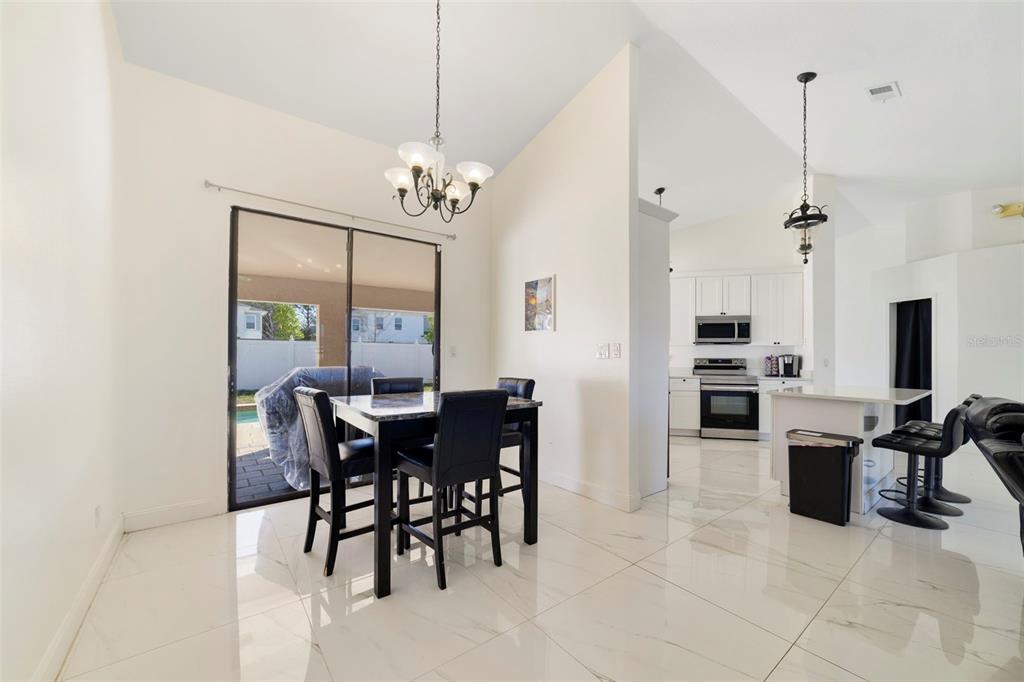 A dining area with tile floors, a chandelier, and a sliding door leading to a patio — 247 COMPETITION DRIVE, KISSIMMEE, FL