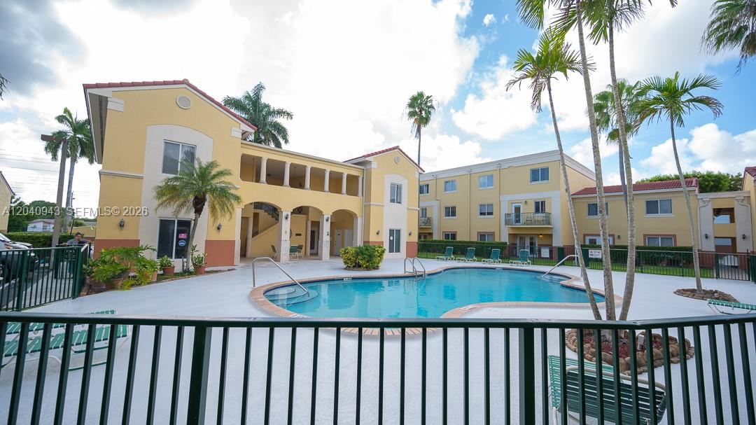 A swimming pool sits in the courtyard of a multi-story yellow apartment complex — 12605 SW 91st St # 204, Miami FL 33186, MIAMI, FL