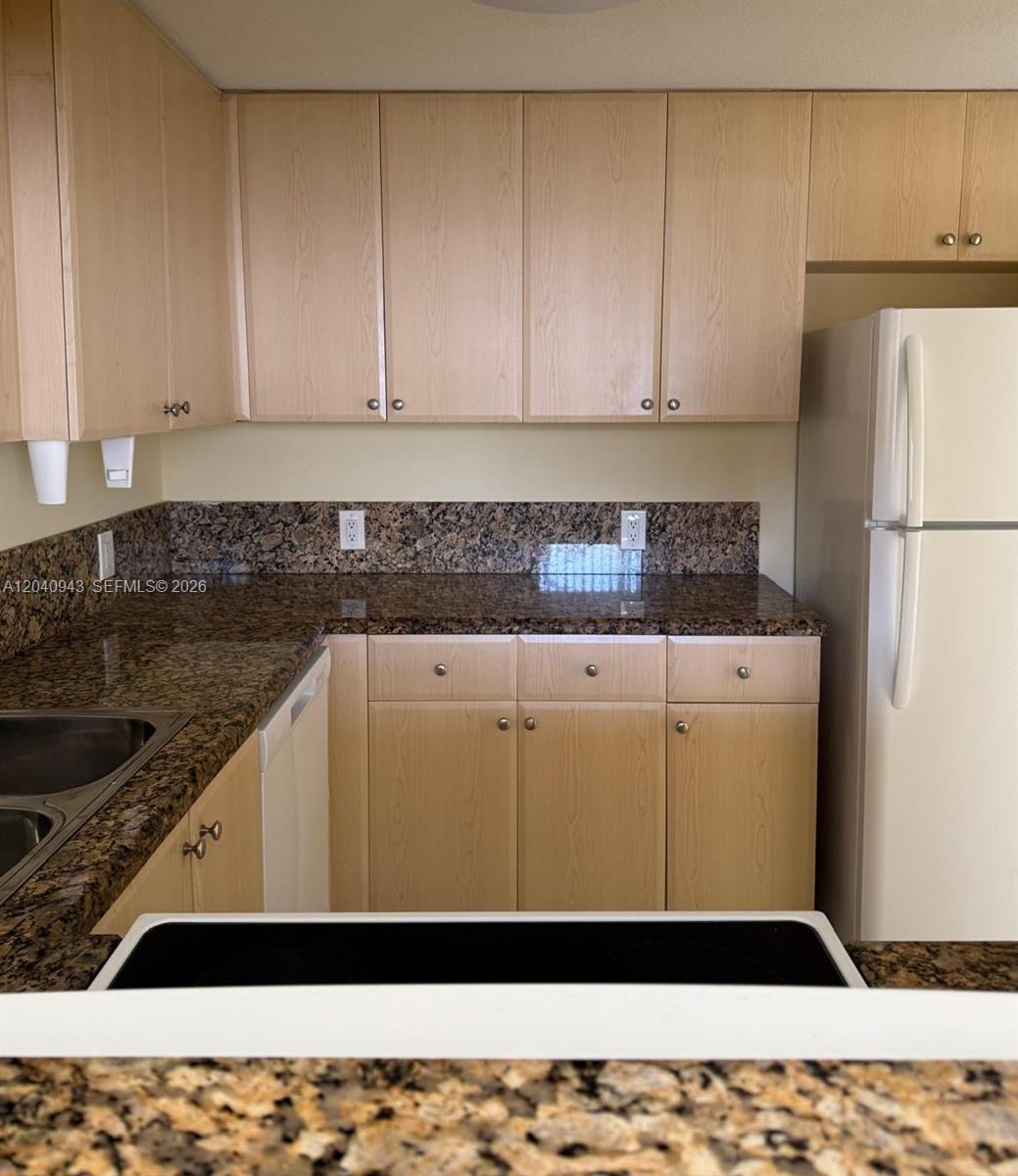 A kitchen features light wood cabinets, dark granite countertops, and a white refrigerator — 12605 SW 91st St # 204, Miami FL 33186, MIAMI, FL