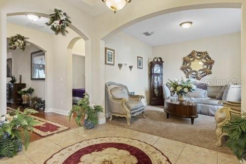 A living room features an arched entryway, a grandfather clock, and a decorative wall mirror — 2858 ROLLING HILLS LANE, APOPKA, FL