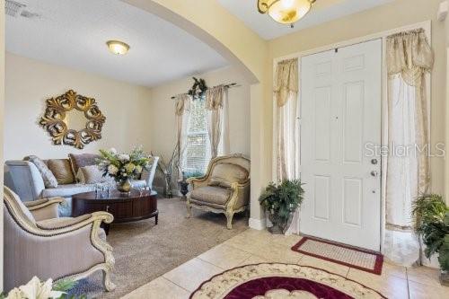 A living room features a white front door, beige carpet, and traditional upholstered furniture — 2858 ROLLING HILLS LANE, APOPKA, FL