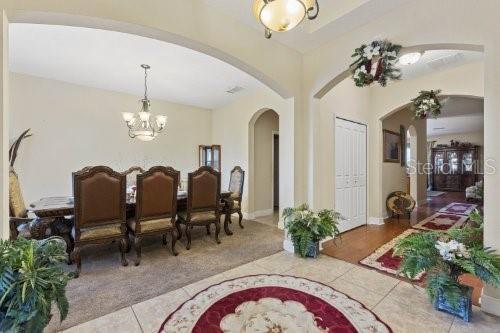 A dining room features a long table, upholstered chairs, a chandelier, and arched entryways — 2858 ROLLING HILLS LANE, APOPKA, FL