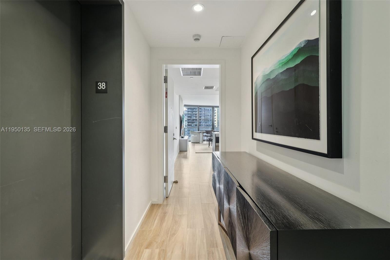 A hallway features a dark console table, a framed landscape print, and a doorway entrance — 801 S Miami Ave # 3802, Miami FL 33130, MIAMI, FL