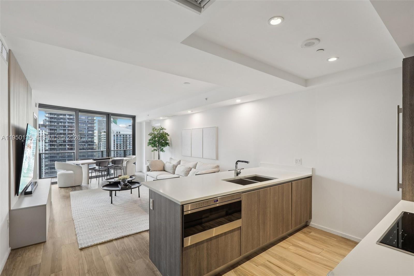 A modern open-concept apartment features a kitchen island, living area, and floor-to-ceiling windows — 801 S Miami Ave # 3802, Miami FL 33130, MIAMI, FL