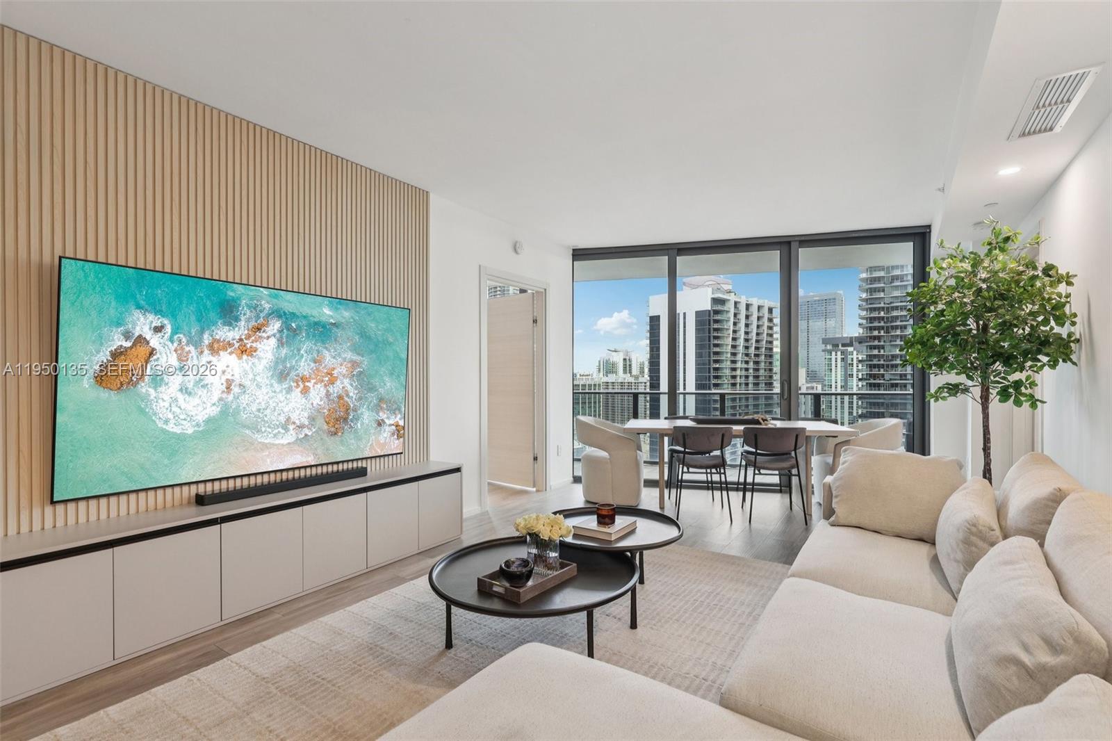 A modern living room features a slatted wood wall, large television, and floor-to-ceiling windows — 801 S Miami Ave # 3802, Miami FL 33130, MIAMI, FL