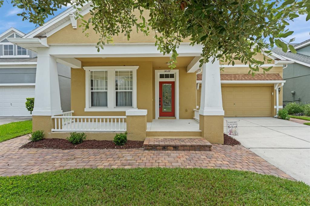 A single-story house with a yellow stucco exterior, a red front door, and a porch — 14127 SOUTHERN RED MAPLE DRIVE, ORLANDO, FL