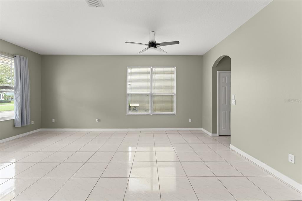 A spacious room features light-colored tile flooring, gray walls, a ceiling fan, and two windows — 14127 SOUTHERN RED MAPLE DRIVE, ORLANDO, FL
