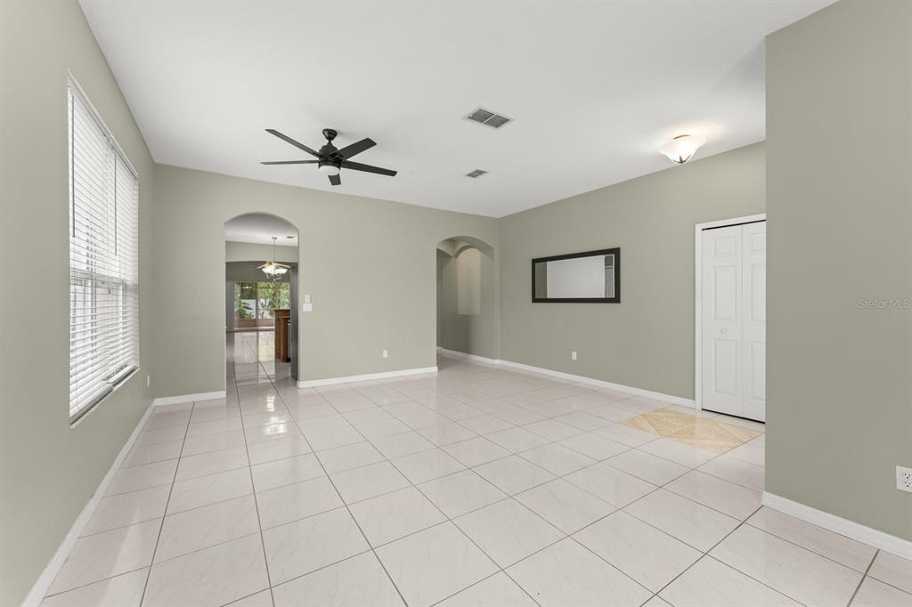 A spacious room with light-colored tile flooring, sage green walls, and a ceiling fan — 14127 SOUTHERN RED MAPLE DRIVE, ORLANDO, FL
