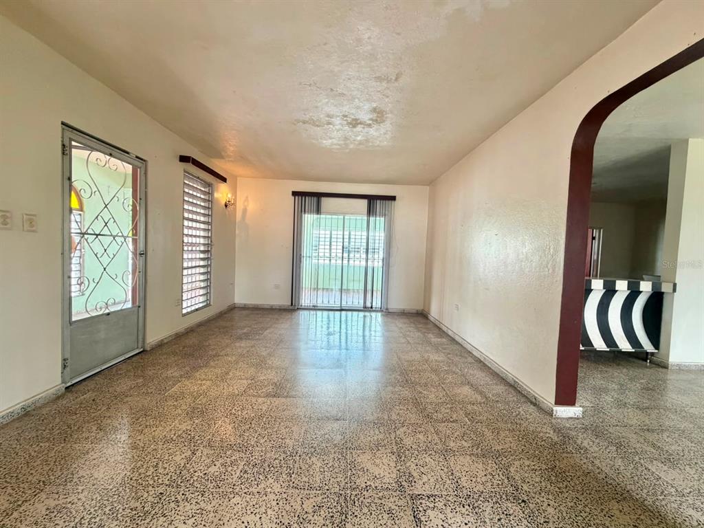 An empty living room with terrazzo flooring, a glass sliding door, and a metal security door — PR 917 KM 1.8, LAS PIEDRAS, PR