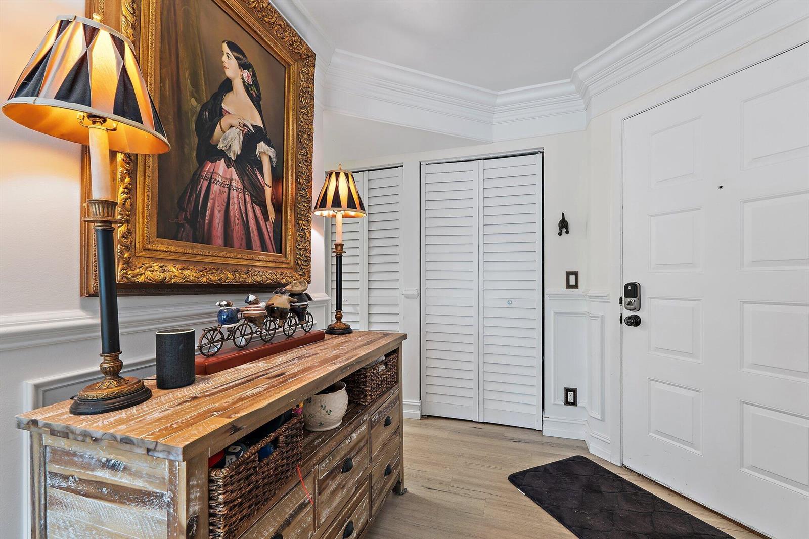 A foyer features a wooden console table, two lamps, a framed portrait, and white doors — 1605 S Us Highway 1 # F202, Jupiter FL 33477, JUPITER, FL