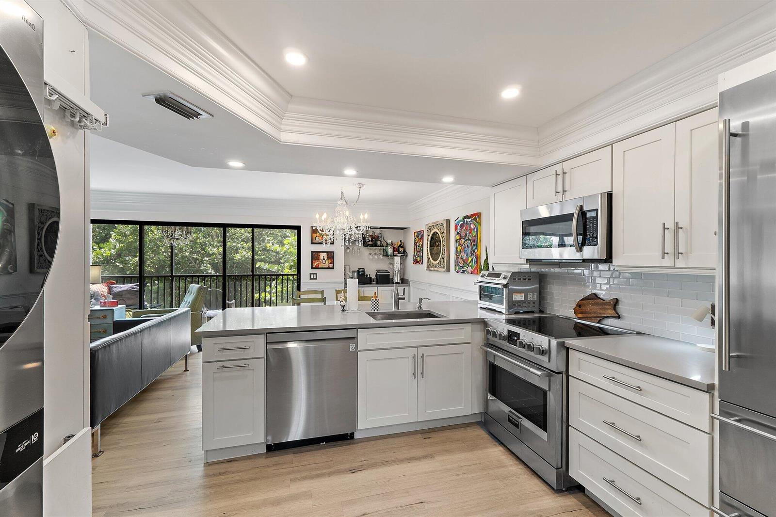 A modern kitchen features white cabinets, stainless steel appliances, and an island with a sink — 1605 S Us Highway 1 # F202, Jupiter FL 33477, JUPITER, FL