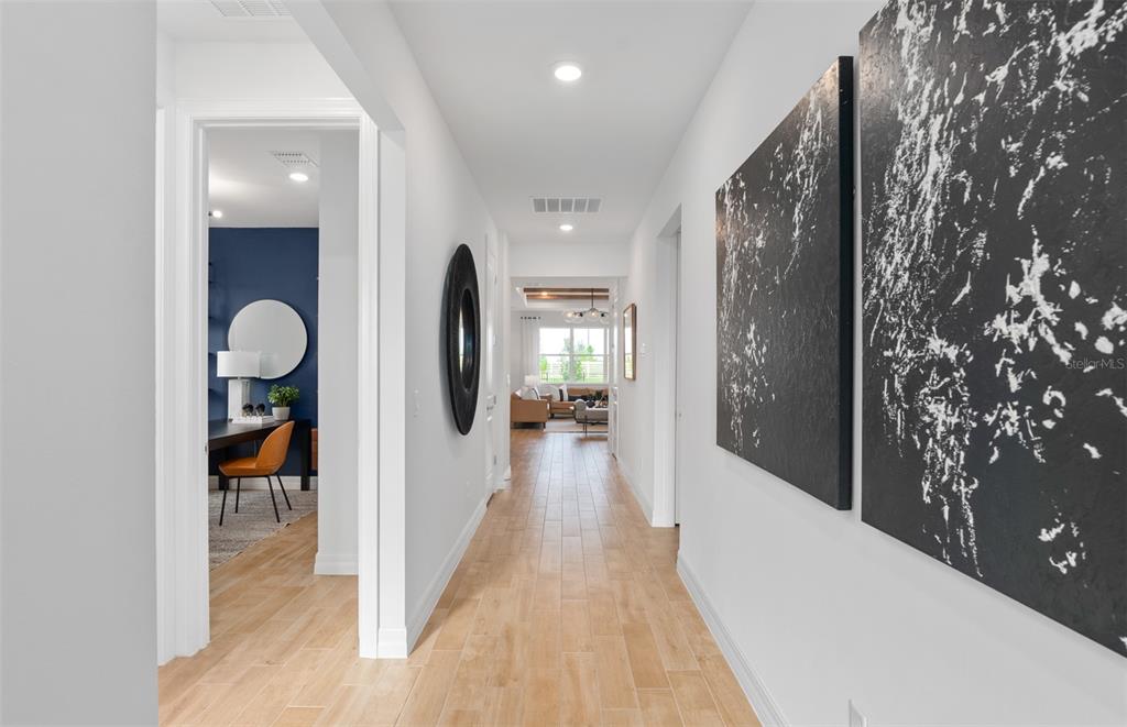 A bright hallway with light wood-look tile flooring leads toward a living area — 2604 SERENITY GARDEN DRIVE, KISSIMMEE, FL