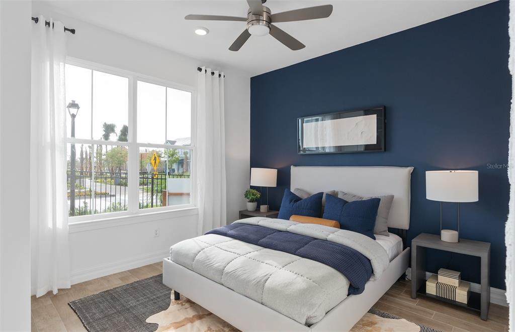 A bedroom features a navy accent wall, a light-colored bed, and a large window — 2604 SERENITY GARDEN DRIVE, KISSIMMEE, FL