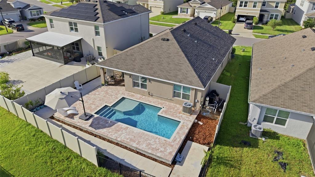 An aerial view shows a house with a backyard swimming pool and a paved patio — 2927 LIVING CORAL DRIVE, ODESSA, FL