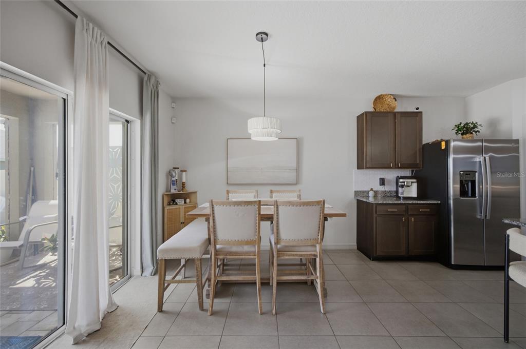 A kitchen features dark wood cabinets, granite countertops, a central island, and three bar stools — 2927 LIVING CORAL DRIVE, ODESSA, FL