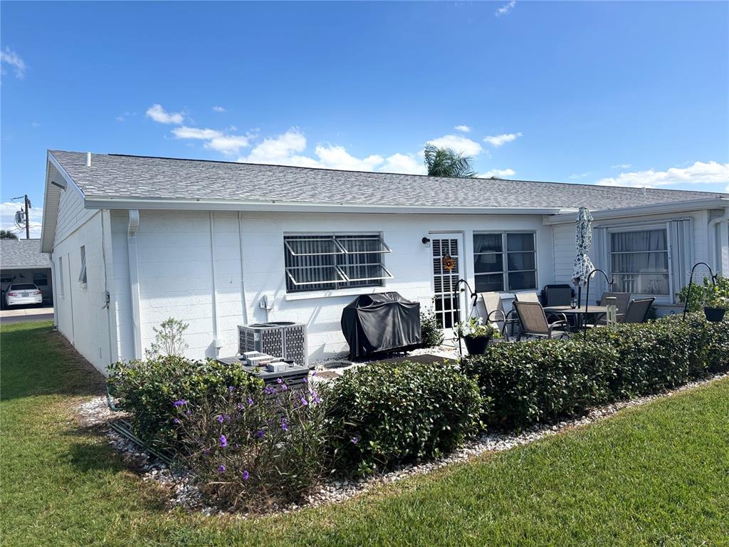 The exterior of a white, single-story house features a patio, landscaping, and a grill — 5983 CORAL WAY, BRADENTON, FL