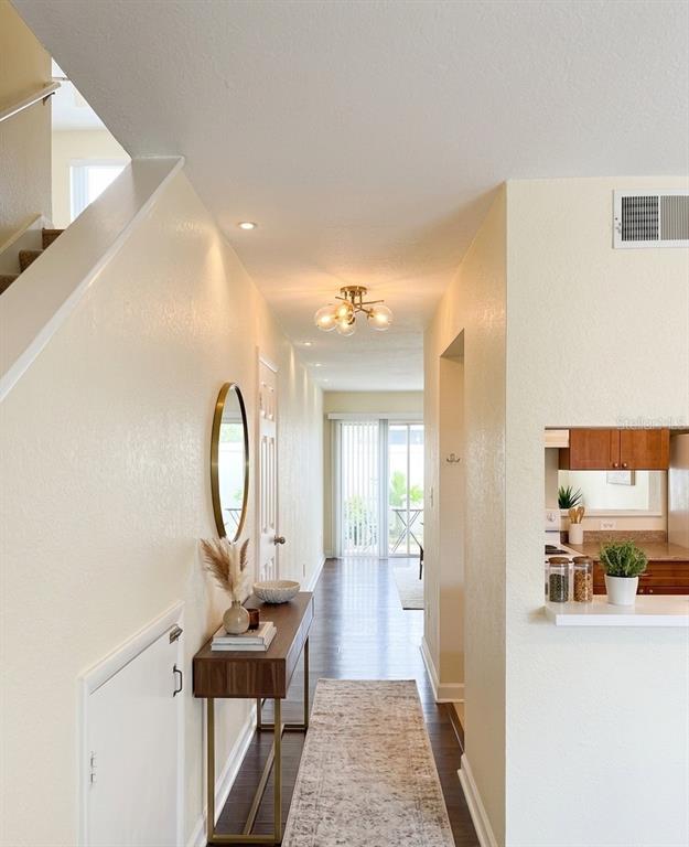 A hallway features a wooden console table, a round mirror, and a modern light fixture — 7143 E BANK DRIVE UNIT 7143, TAMPA, FL