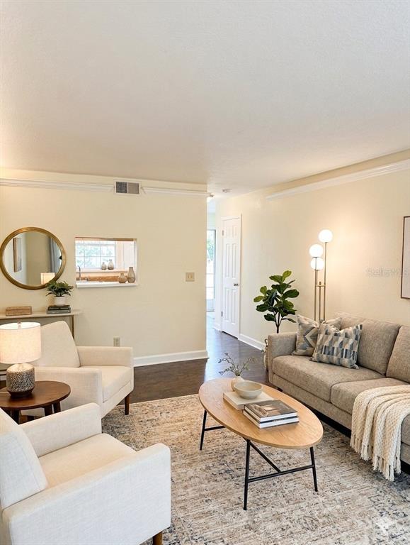 A living room features two armchairs, a sofa, an oval coffee table, and a pass-through window — 7143 E BANK DRIVE UNIT 7143, TAMPA, FL