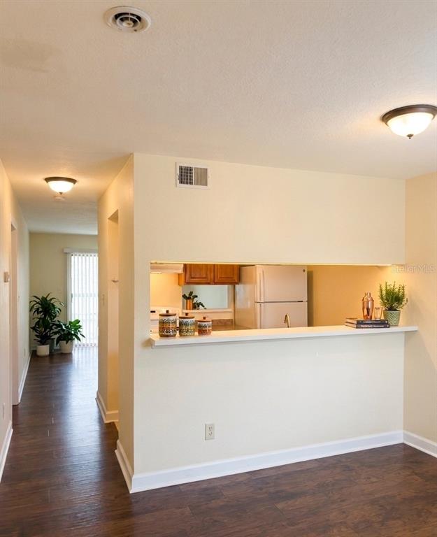 A kitchen with a pass-through window overlooks a dining area with dark wood flooring — 7143 E BANK DRIVE UNIT 7143, TAMPA, FL