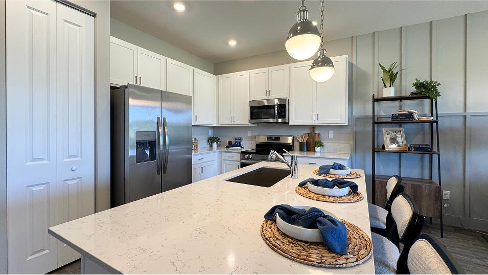 A kitchen features white cabinets, stainless steel appliances, and a large quartz-topped island — 3640 Spanish Cedar Place, Fort Pierce FL 34946, FORT PIERCE, FL