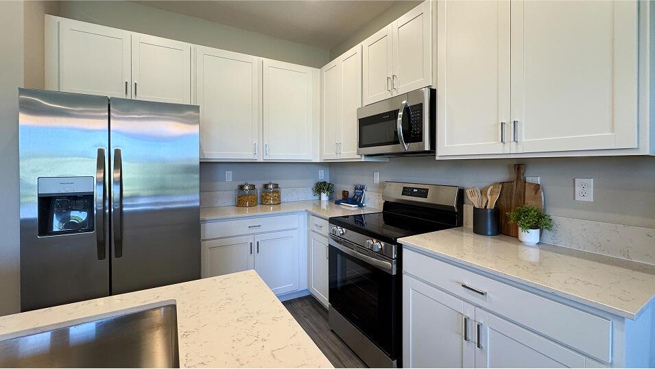 A kitchen features white cabinets, stainless steel appliances, and light-colored quartz countertops — 3640 Spanish Cedar Place, Fort Pierce FL 34946, FORT PIERCE, FL