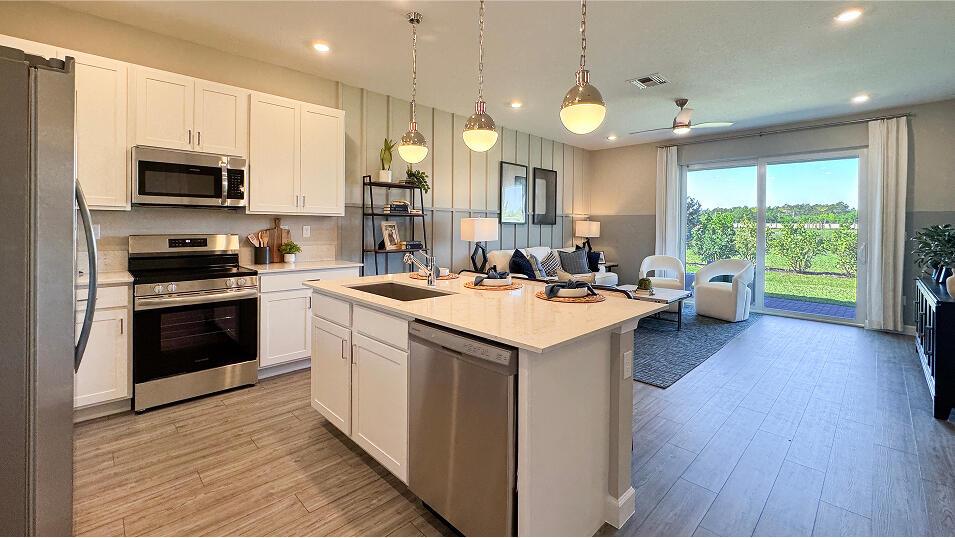 A kitchen with white cabinets and a center island opens into a living area — 3640 Spanish Cedar Place, Fort Pierce FL 34946, FORT PIERCE, FL