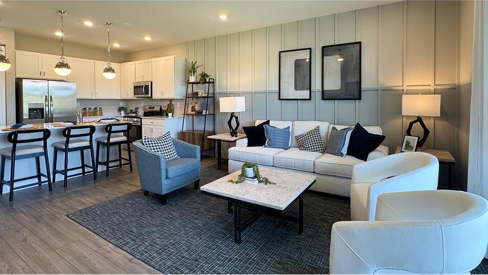 A modern open-concept living room features a kitchen with white cabinetry and a seating area — 3640 Spanish Cedar Place, Fort Pierce FL 34946, FORT PIERCE, FL