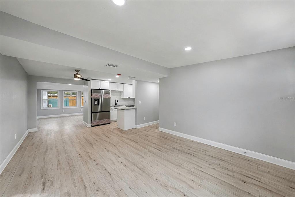A bright, open-concept living area features light wood-look flooring, gray walls, and a modern kitchen — 2162 BARCELONA DRIVE, CLEARWATER, FL