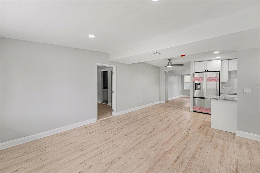 A bright room with light wood-look flooring, gray walls, and an open kitchen area — 2162 BARCELONA DRIVE, CLEARWATER, FL