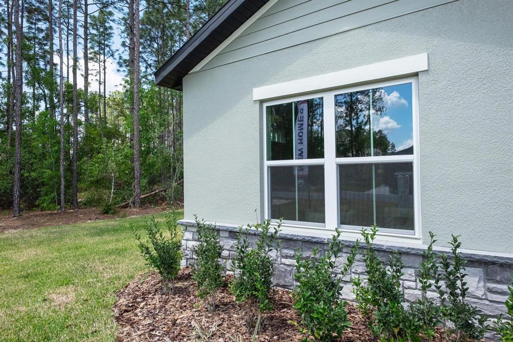 The exterior of a house features light green stucco, stone veneer, and a double-hung window — 15645 SW 19TH TERRACE, OCALA, FL