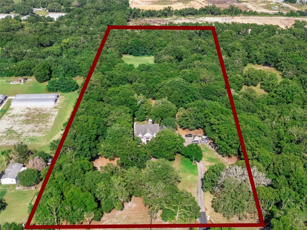 An aerial view shows a house nestled within a large, wooded lot outlined in red — 4275 ROUND LAKE ROAD, APOPKA, FL