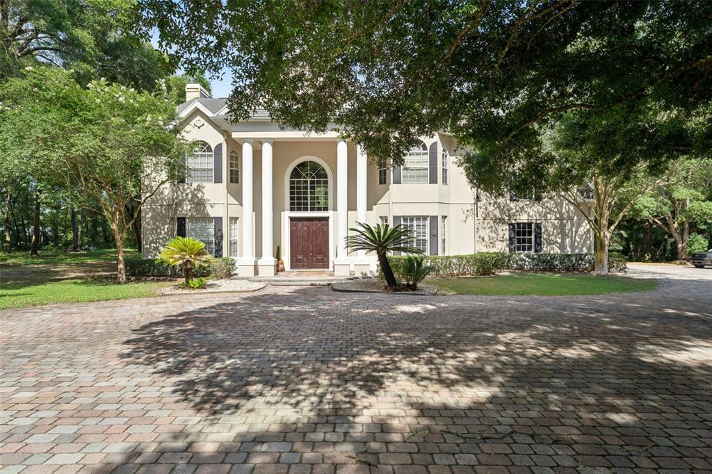A two-story house with white columns and a brick driveway surrounded by large trees — 4275 ROUND LAKE ROAD, APOPKA, FL