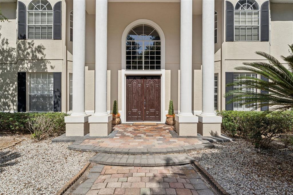 The front entrance of a house features a paved walkway, four white columns, and double doors — 4275 ROUND LAKE ROAD, APOPKA, FL